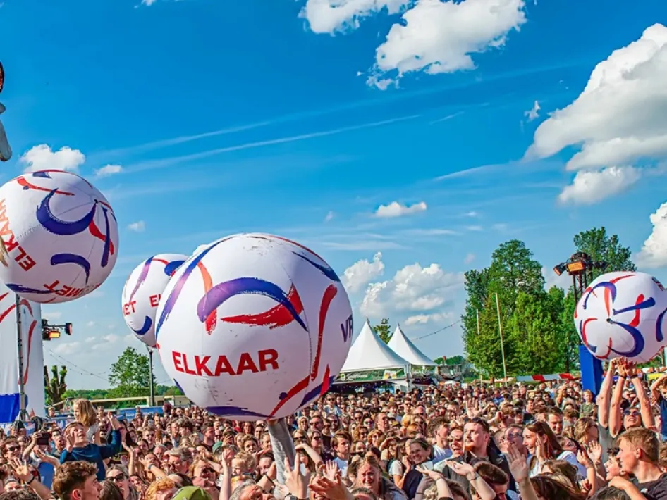 Bevrijdingsfestival Roermond met een grote menigte bezoekers die samen feest vieren en ballen omhoog houden tijdens een optreden in de buitenlucht.