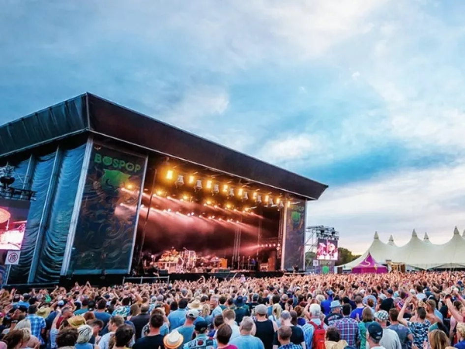 Publiek voor het hoofdpodium tijdens Bospop Festival in Weert met een band die optreedt onder podiumlichten.
