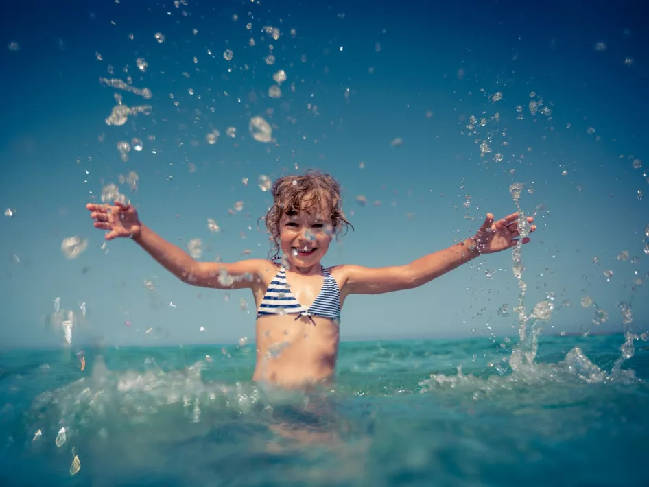 Meisje laat het water omhoog spatten bij dagstrand de Maasterp