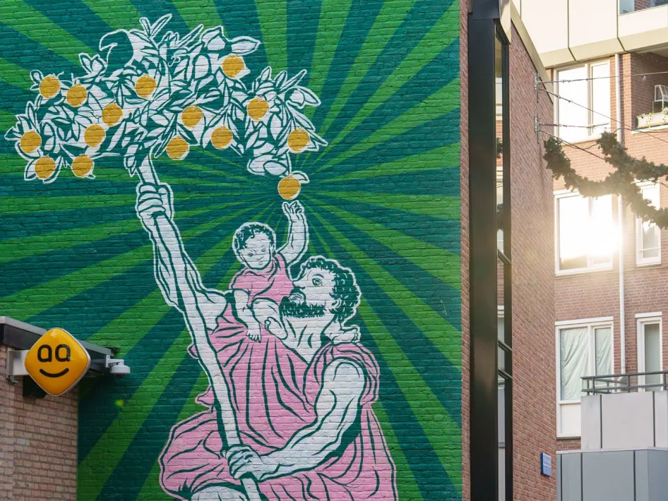 Muurschildering van een man met een kind op zijn schouder die een tak met sinaasappels omhooghoudt tegen een groene achtergrond.