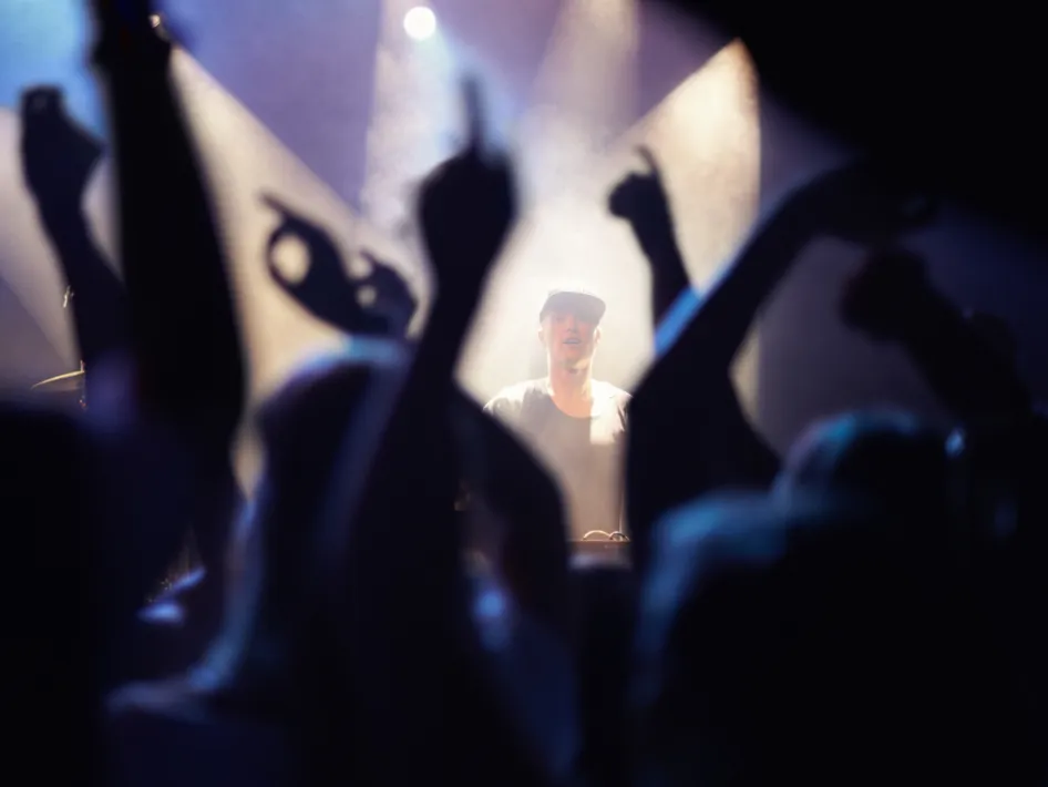 Sfeerbeeld van Op Hop van Zegen in Roermond met publiek dat juicht en een DJ op het podium tijdens het bierfestival.