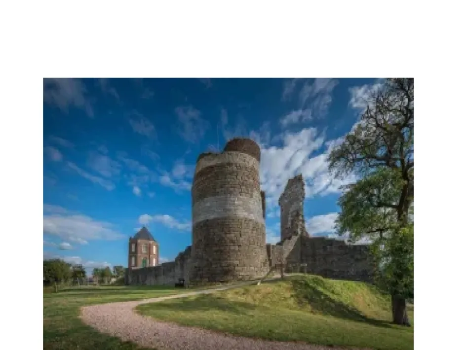Kasteel Montfort met ronde toren en ruïne, gelegen in een groen landschap onder een blauwe lucht.