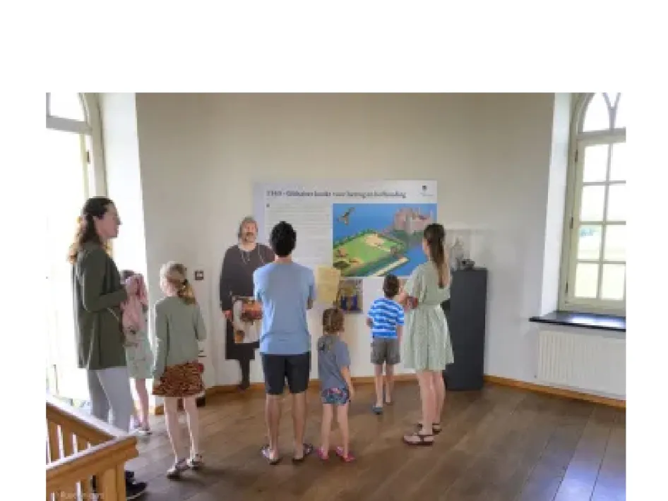 Bezoekers bekijken met kinderen een informatiepaneel in Kasteel Montfort.