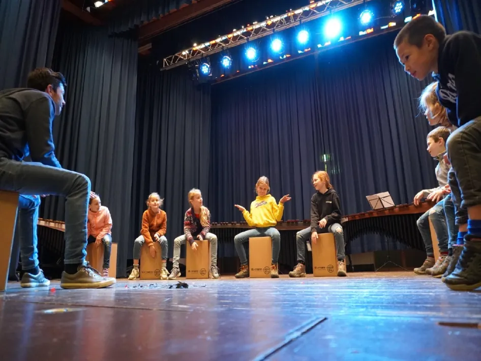 kinderen die zitten op blokken tijdens voorbereiding op het knutselconcert