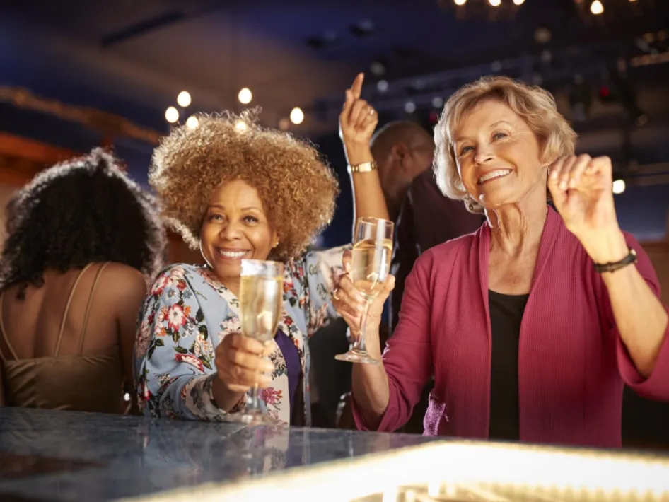 twee dames van middelbare leeftijd vieren ladies night met een glaasje aan de bar