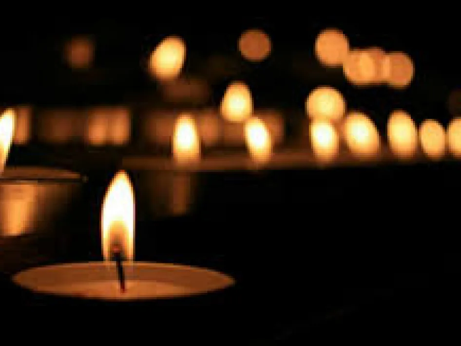 Brandende kaarsen tijdens Lichtjes op kerstavond 2025 bij een herdenking in het donker, symbool voor herinnering en verbondenheid.