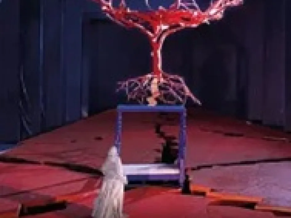 Scènebeeld uit de opera El Último Sueño de Frida y Diego met een rood vertakte boomconstructie boven het toneel en een witte figuur op de voorgrond.