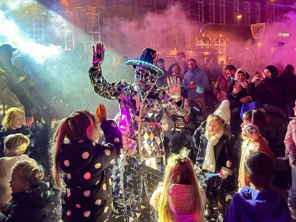 Lichtartiest in spiegelkostuum tussen bezoekers tijdens Roermond vol Licht.