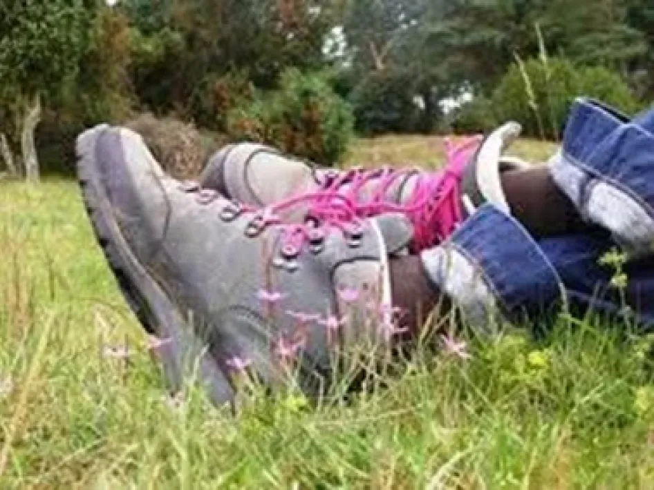Wandelschoenen in het gras in Baarlo tijdens een voorjaarswandeling, met bloeiende bloemen en groen landschap op de achtergrond.