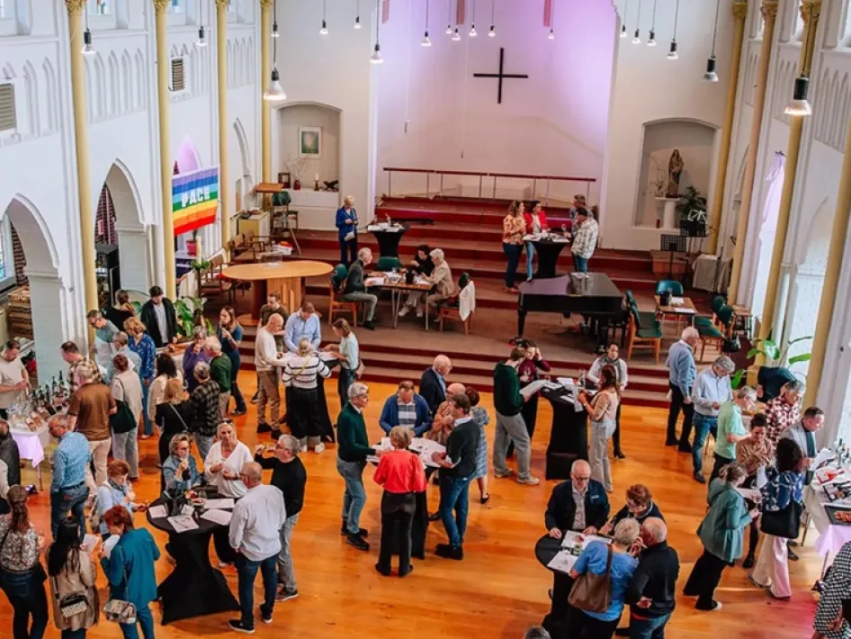 Voorjaarsproeverij Henri Bloem in een sfeervolle kerkruimte waar bezoekers langs tafels lopen en samen genieten van wijn en lokale producten.