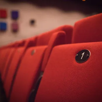 Close-up van een rode theaterstoel met stoelnummer 1 in een lege zaal van de Bombardon 