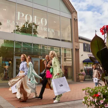 Vrolijke groep vrouwen met shoppingtassen loopt langs de Polo Ralph Lauren winkel bij Designer Outlet Roermond tijdens het Friends & Family Event.