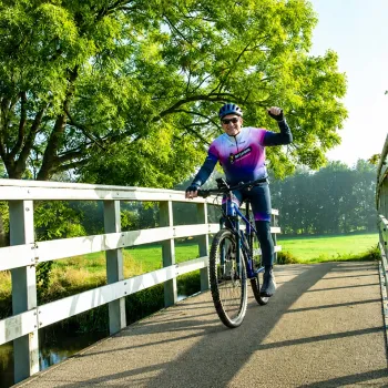 Deelnemer aan de Heksenheuveltocht fietst over een brug in het groene landschap van Nederweert tijdens de mountainbike- en graveltocht.