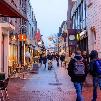 Menschen bummeln und shoppen durch eine stimmungsvoll beleuchtete Einkaufsstraße im Zentrum – beim verkaufsoffenen Sonntag in Weert.