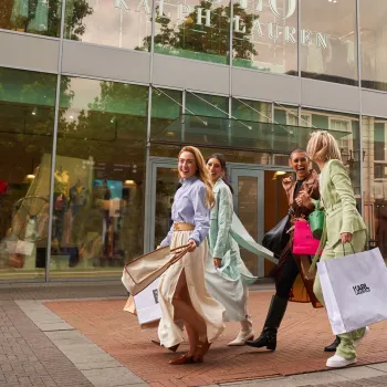 Four women with shopping bags in front of Ralph Lauren during Late Night Shopping at Designer Outlet Roermond.