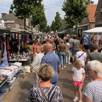 Drukke Luikse markt in Linne met bezoekers tussen marktkramen met kleding, huishoudelijke spullen en andere koopwaar.