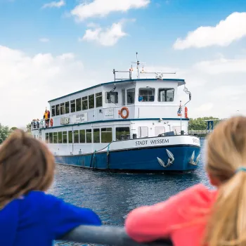 Twee meisjes kijken hoe de rondvaartboot aanmeert voor de rondvaart de Maasparel Tocht