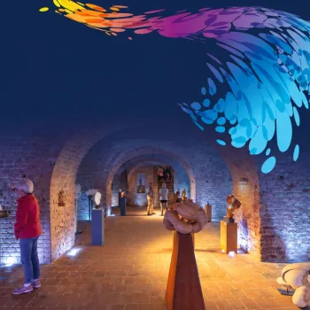 Bezoekers bekijken kunstwerken in een historische expositieruimte tijdens Kunststroom Roerdalen Wassenberg.
