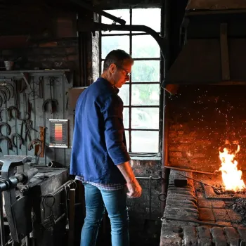 Smid aan het werk bij een brandend smidsvuur tijdens Smedendag van Eynderhoof.