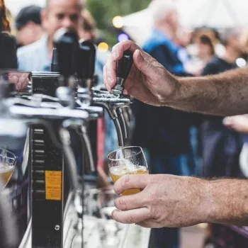 Beer being poured at the Op Hop van Zegen festival in Roermond, with people in the background on a lively festival site.
