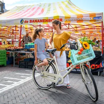 Mutter und Tochter mit Fahrrad vor einem Marktstand auf dem Wochenmarkt Roermond.
