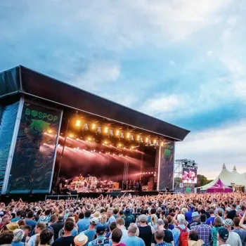 Publiek voor het hoofdpodium tijdens Bospop Festival in Weert met een band die optreedt onder podiumlichten.