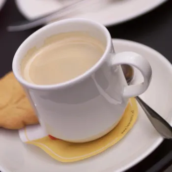 koffie in een witte kop, een koekje en een lepeltje op een wit schoteltje van de high tea