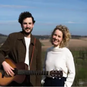 Duo met gitaar poseert buiten in een heuvelachtig landschap voor een appeltaartconcert.