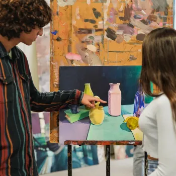 Bezoekers bekijken kunstwerken tijdens Art in the Yard en staan samen bij een kleurrijke installatie.
